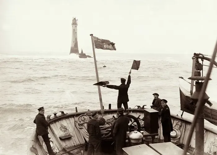 Framed Print : A crewman semaphores a signal from the Trinity House tender to the Wolf Rock Lighthouse