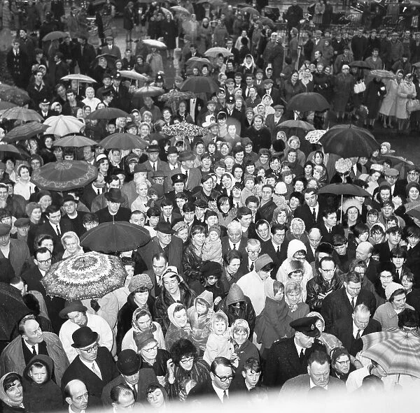 Crowds gather in the rain to catch a glimpse of Prime Minister Harold Wilson (1916 - 1995