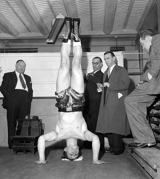 Cruiser weight boxer George walker doing a head stand at the weigh in November 1957