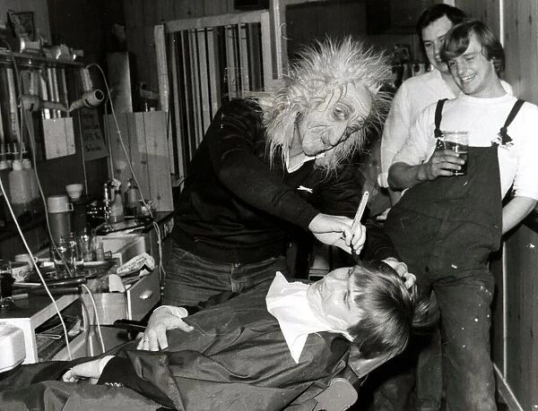 A customer sits in the barbers chair having his faced shaved by a man in a mask at Steve