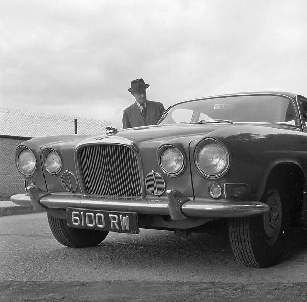Daily Herald motor racing correspondent Thomas H Wisdom standing beside a new Jaguar Mark