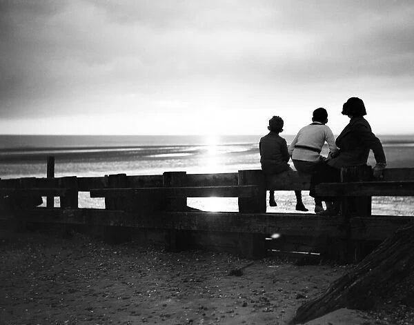 Darkness falls around three children as they watch the sunset at Rye Bay, Sussex
