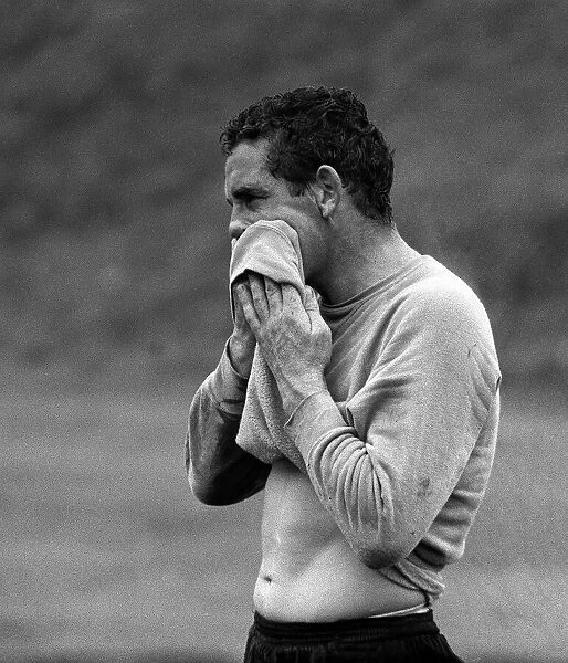 Dave Mackay of spurs wipes the sweat off with his shirt after a heavy training session