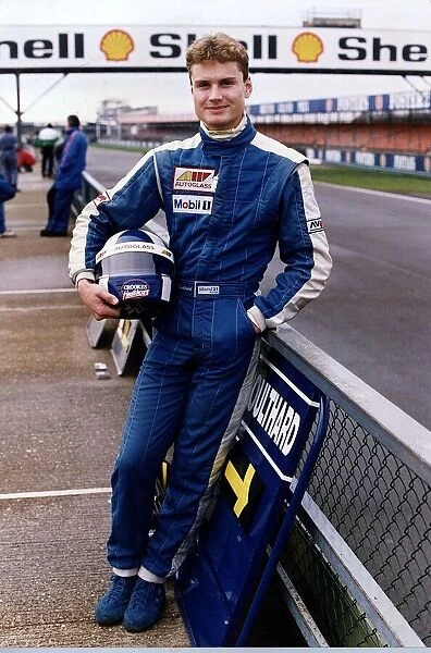 David Coulthard leaning on fence at race track holding helmet racing Formula 3000
