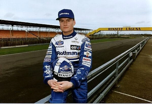 David Coulthard sitting on fence at race track holding helmet Formula One racing