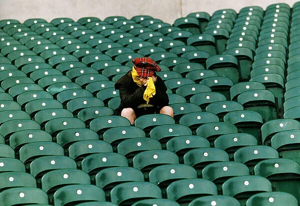 A dejected Scotland fan sits in a stadium with his head in his hands after his teams
