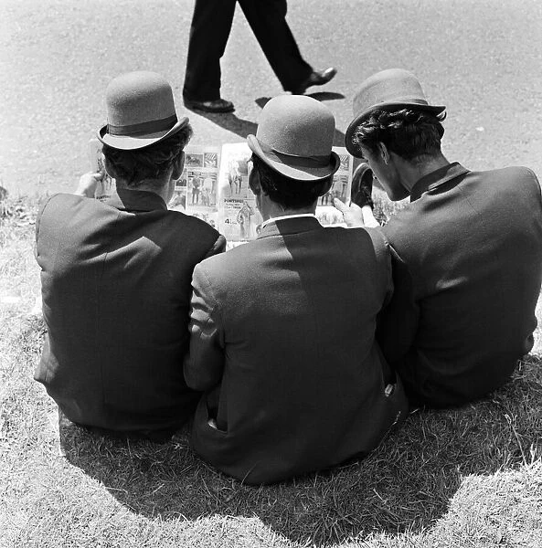 Derby Day at Epsom. Pictured, three lads from Newmarket sitting on the grass studying