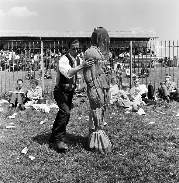 Derby Day at Epsom. Pictured, a strong man wrapped in chains. 3rd June 1959