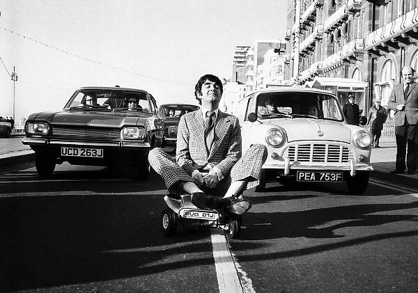 Derek Nimmo actor in Brighton riding a toy car dbase msi