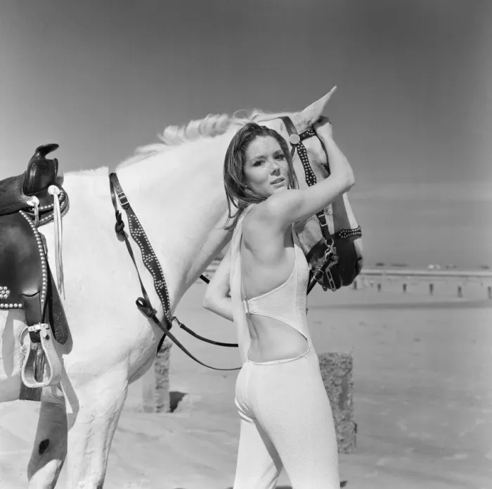 Framed Print : Diana Rigg, who plays Emma Peel, looking serious to camera with a white horse