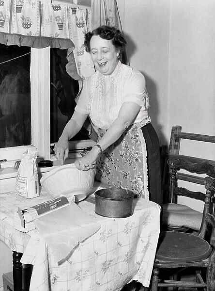 Domestic scenes: A woman making cakes in her kitchen at home. 1954
