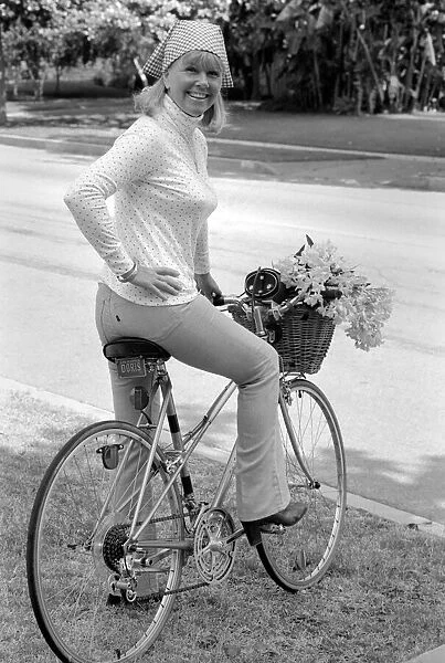 Doris Day seen holding a bunch of flowers on her bicyle
