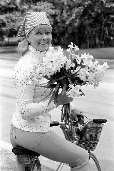 Doris Day seen holding a bunch of flowers on her bicyle