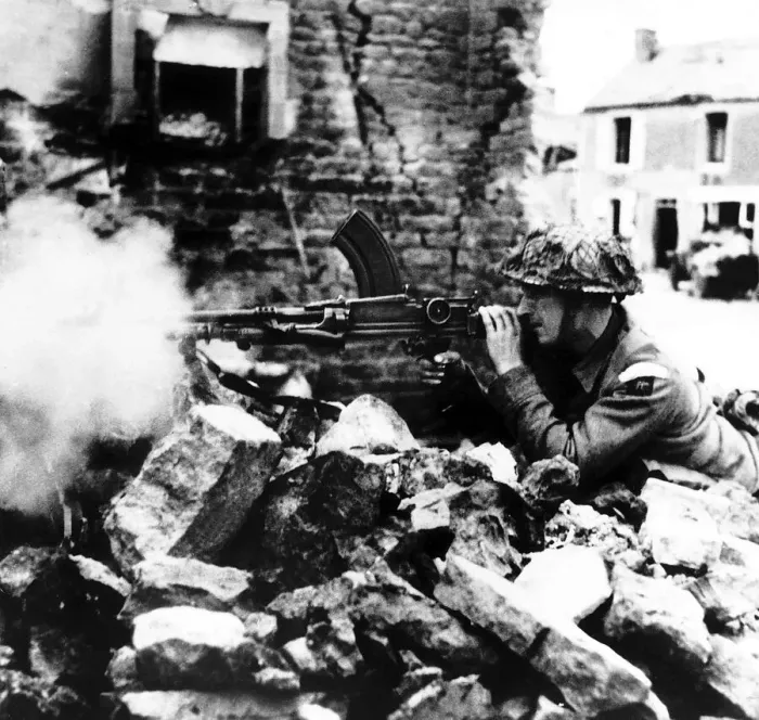 Framed Print : Dorset Regiment soldier fires a machine gun as they battle through a French village Framed Print : Dorset Regiment soldier fires a machine gun as they battle through a French village