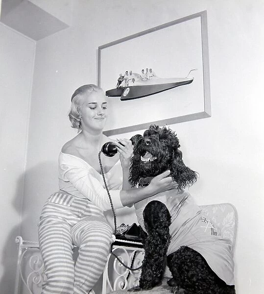 Dory Swan and her pet dog talking on the telephone Circa 1955
