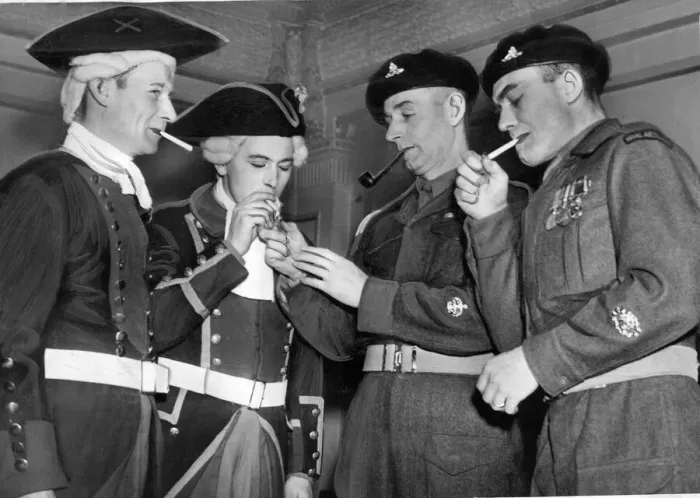 Framed Print : Dressed for battle, the two gunners from the past, share a light with todays soldiers in