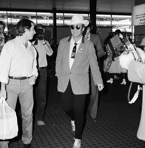 Dressed in a stetson hat, Elton John leaves Heathrow Airport for America