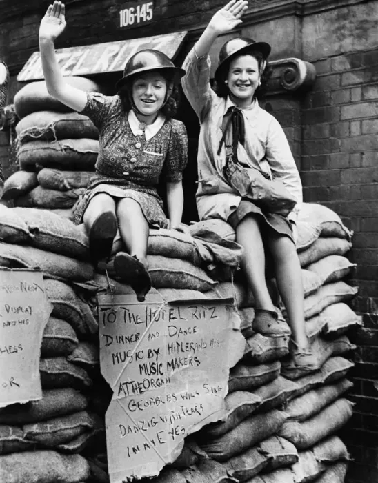 Framed Print : East End Ritz hotel, two women sitting on sand bags waving to the camera