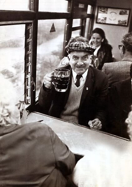 An elderley man enjoying a pint of beer on a Ffestiniog Railway train in North Wales