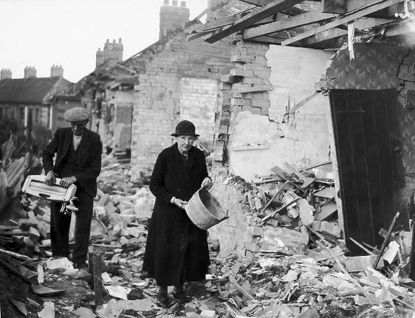 An elderly couple clear away the rubble near their homes after an air raid by the German