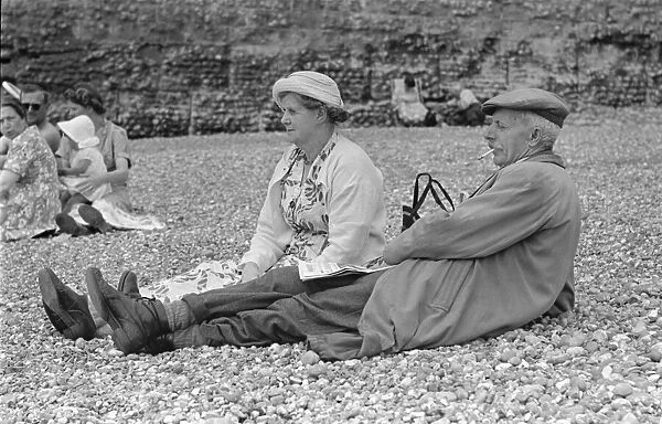 Elderly couple sunbathing on the pebble beach at Brighton July 1958