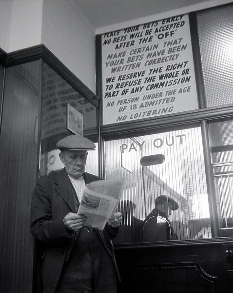 An elderly man studies the form guide inside A E Fane and Co betting shop in Islington