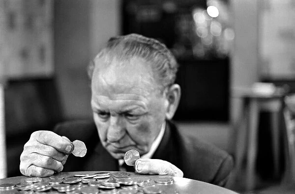 Elderly man studying a new fifty pence close up. November 1969 Z11025-004