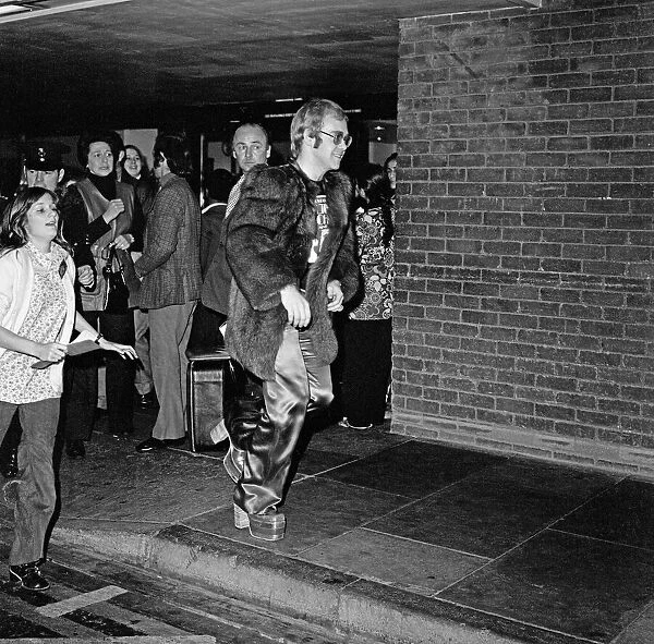 Elton John arrives at Heathrow Airport, and has to run from the crowds of fans who are