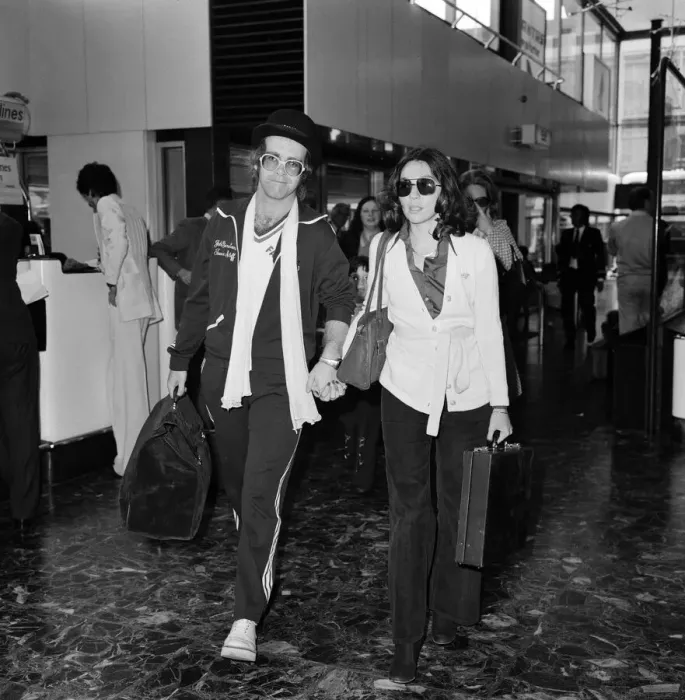 Framed Print : Elton John leaving Heathrow airport hand in hand with Connie Papras Framed Print : Elton John leaving Heathrow airport hand in hand with Connie Papras