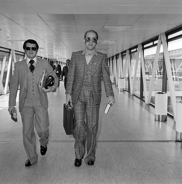 Elton John, with his manager John Reid, leaving Heathrow Airport for Helsinki where he
