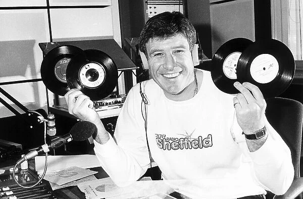 Emlyn Hughes of Liverpool January 1988 holding up records ashe does his DJ bit at