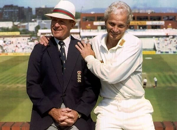 England cricketer David Gower sitting on a brick wall with commentator