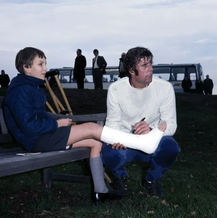 Framed Print : England footballer Geoff Hurst signs an autograph for a young fan in plaster caste during Framed Print : England footballer Geoff Hurst signs an autograph for a young fan in plaster caste during