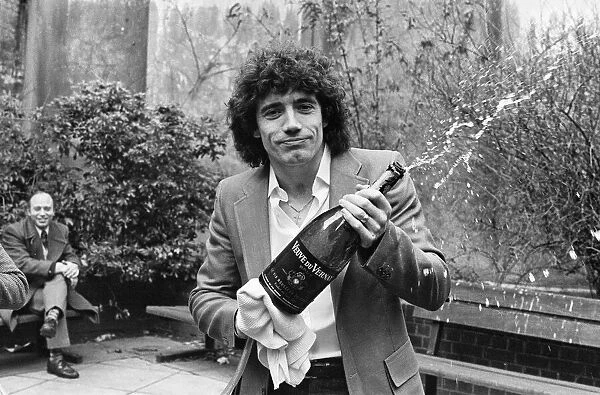 England footballer Kevin Keegan poses for photographers holding a large champagne bottle