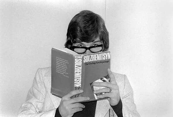 England footballer Malcolm MacDonald clowns around with glasses whilst reading '