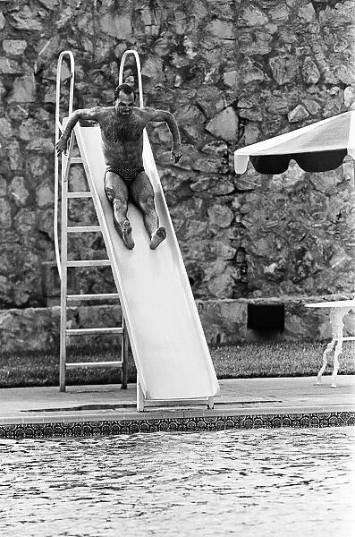 England footballer Ray Wilkins slides into the swimming pool at the Cima Club in