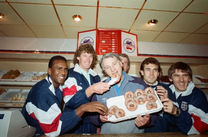 Framed Print : England manager Bobby Robson enjoying a selection of doughnuts with members of his Framed Print : England manager Bobby Robson enjoying a selection of doughnuts with members of his
