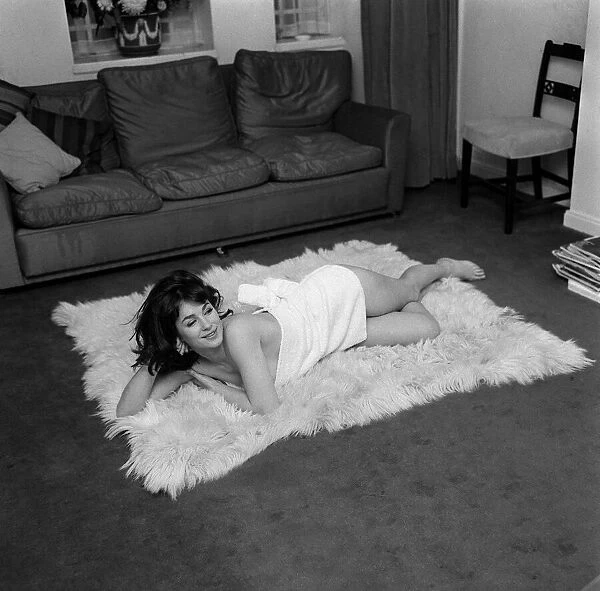 English actress Shirley Anne Field laying on sheepskin carpet dressed only in short towel