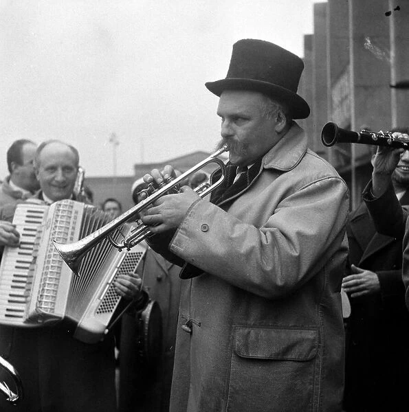 Entertainer Jimmy Edwards wearing a top hat, and his group of buskers entertaining