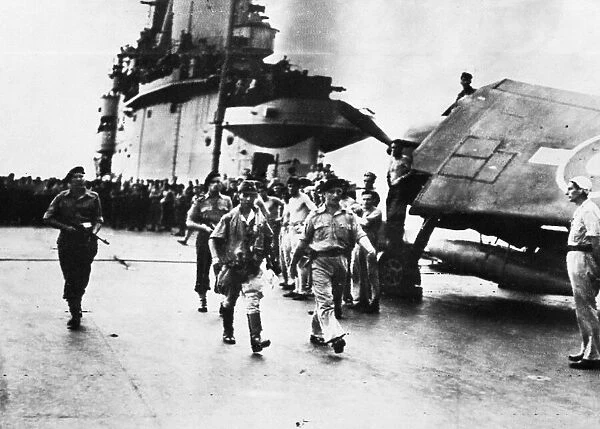 Envoy Makimura walks down the flight deck of H. M. S. Indomitable after discussing