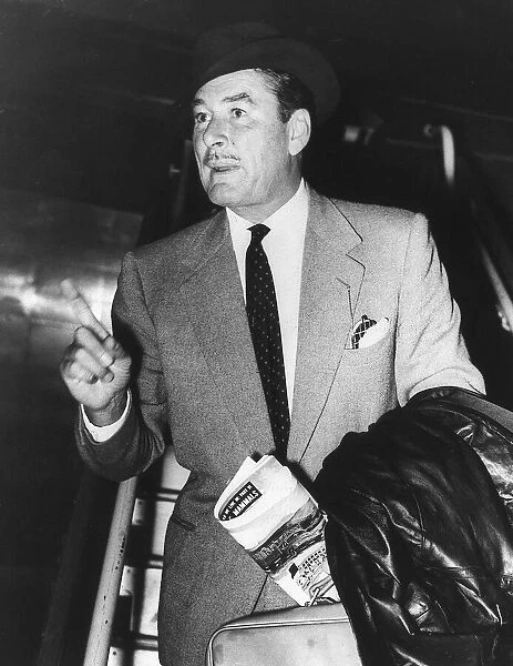 Errol Flynn pointing his finger and holding a suitcase and a news paper with a black