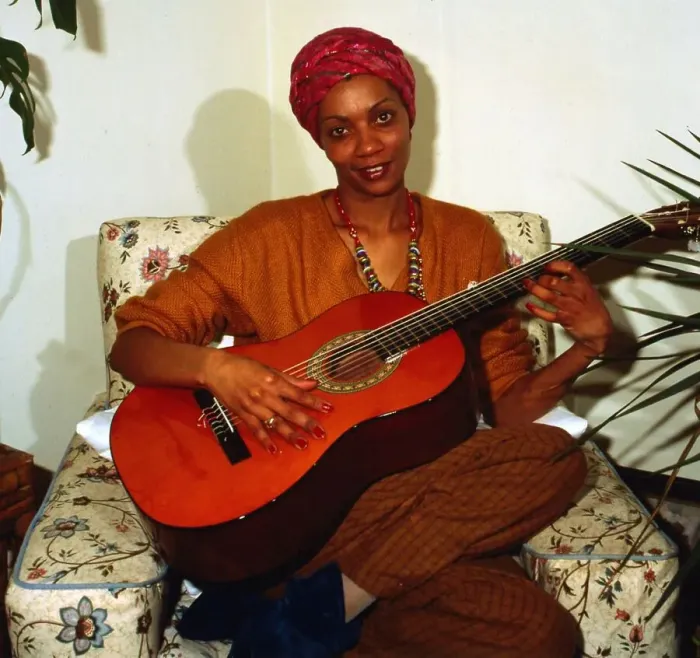 Framed Print : Eva Mottley sitting on chair playing guitar April 1983 Framed Print : Eva Mottley sitting on chair playing guitar April 1983