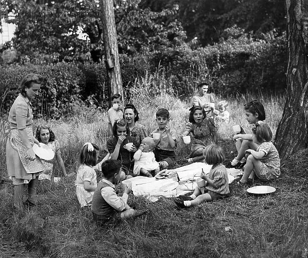 Evacuees having a picnic under the cedar trees in the gardens of a church in Woburn Sands