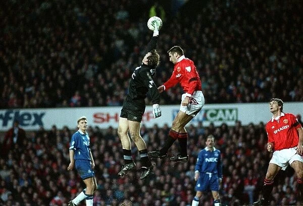 Everton goalkeeper Neville Southall catches the ball with Eric Cantona jumping Manchester