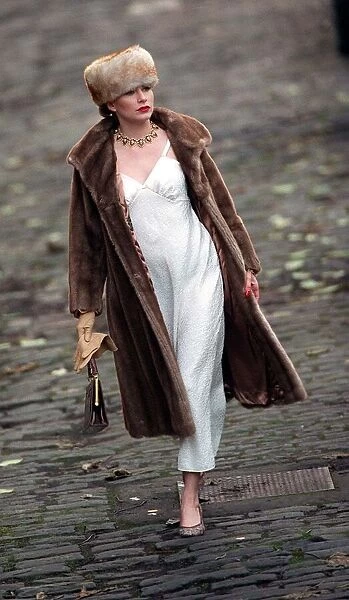 Evita Fashion Model wearing brown fur coat and hat white slip dress handbag gold