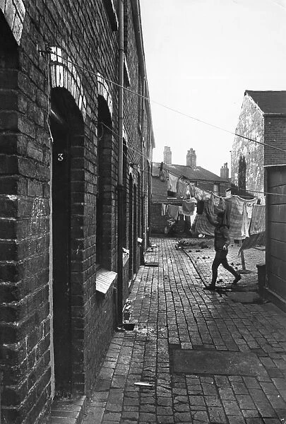 Exterior view of a Birmingham terraced house showing a woman hanging out her laundry