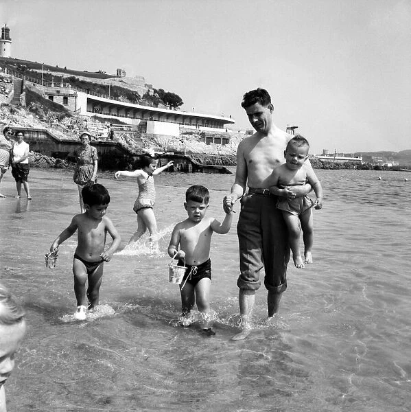 Families on the beach at Plymouth Man paddling in the sea with his three sons