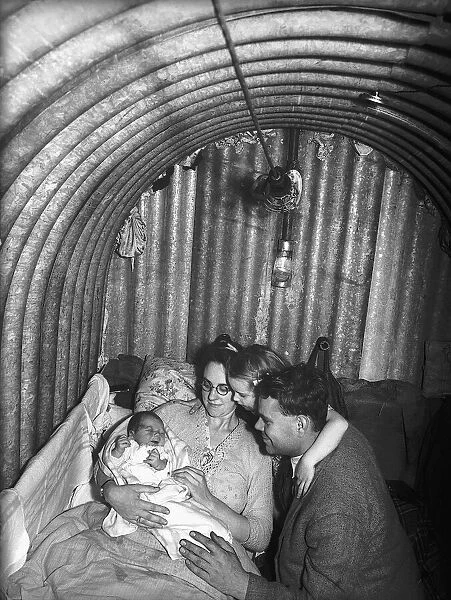 A family inside their air-raid shelter during WW2, with the mother cradling her new born