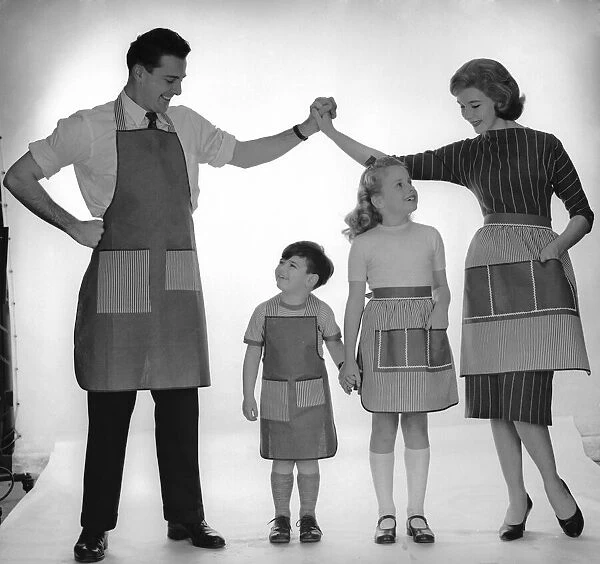 Family modelling a set of aprons for Reveille. 2nd December 1957