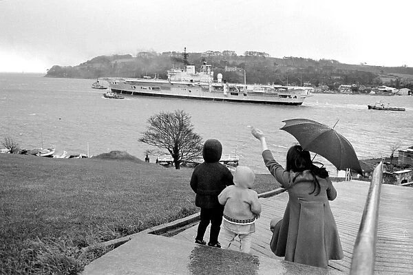 A family stand in the rain as they wave to Aircraft carrier HMS Ark Royal on preliminary